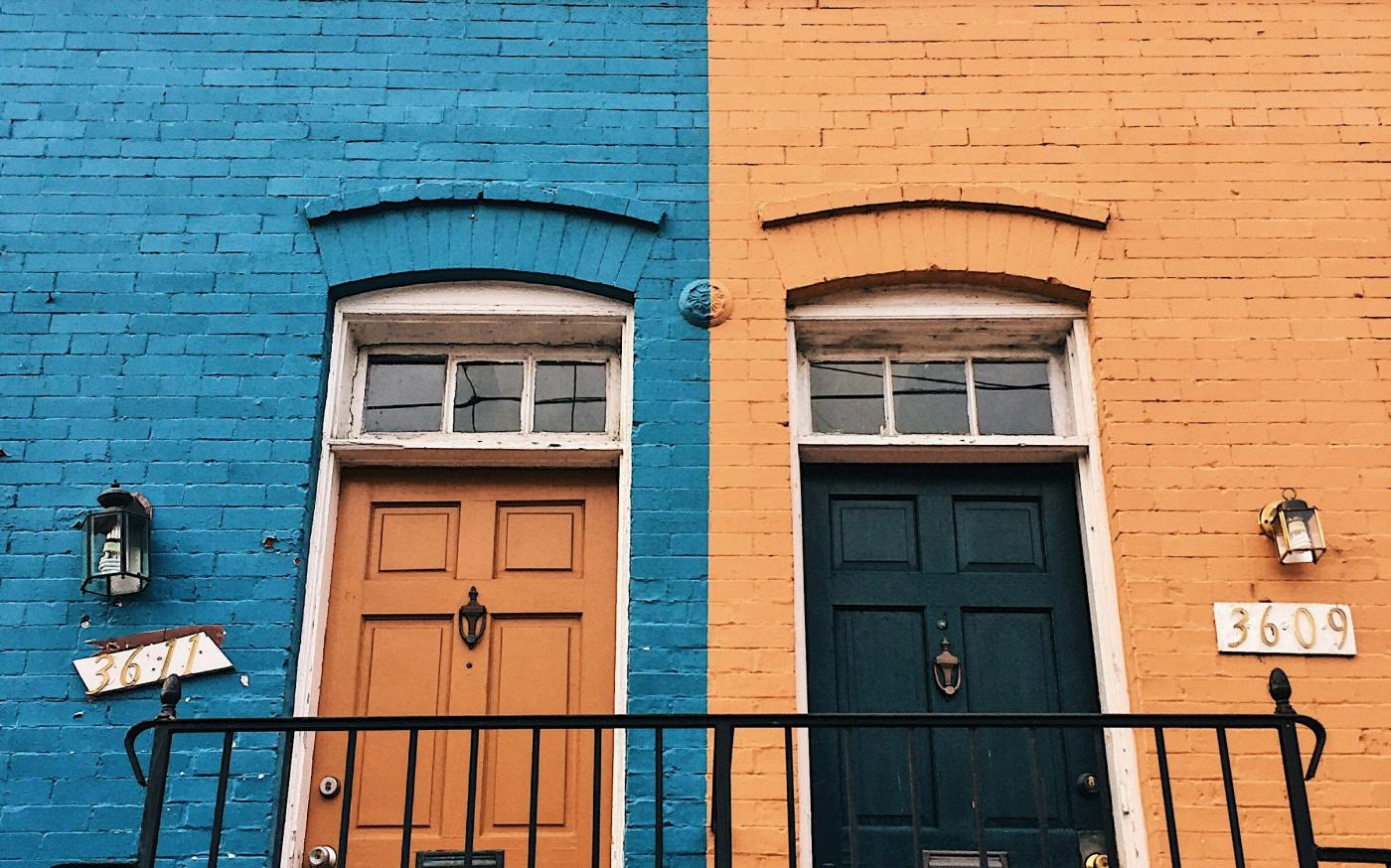 a blue building with a black door by Meg Jenson courtesy of Unsplash.