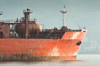 Large red cargo ship sails on the water by Adem Percem courtesy of Unsplash.